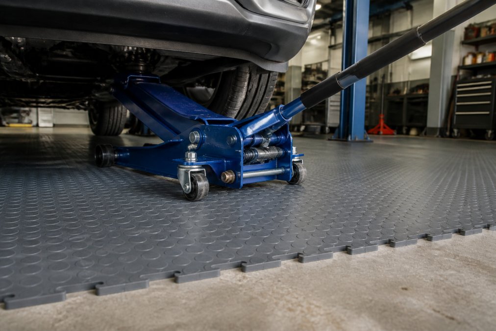 Modulære gulvfliser: Er de pengene værd? 2 Close-up af modulær PVC-flise under tungt værkstøj i garage med beton- gulv og industrielt lys