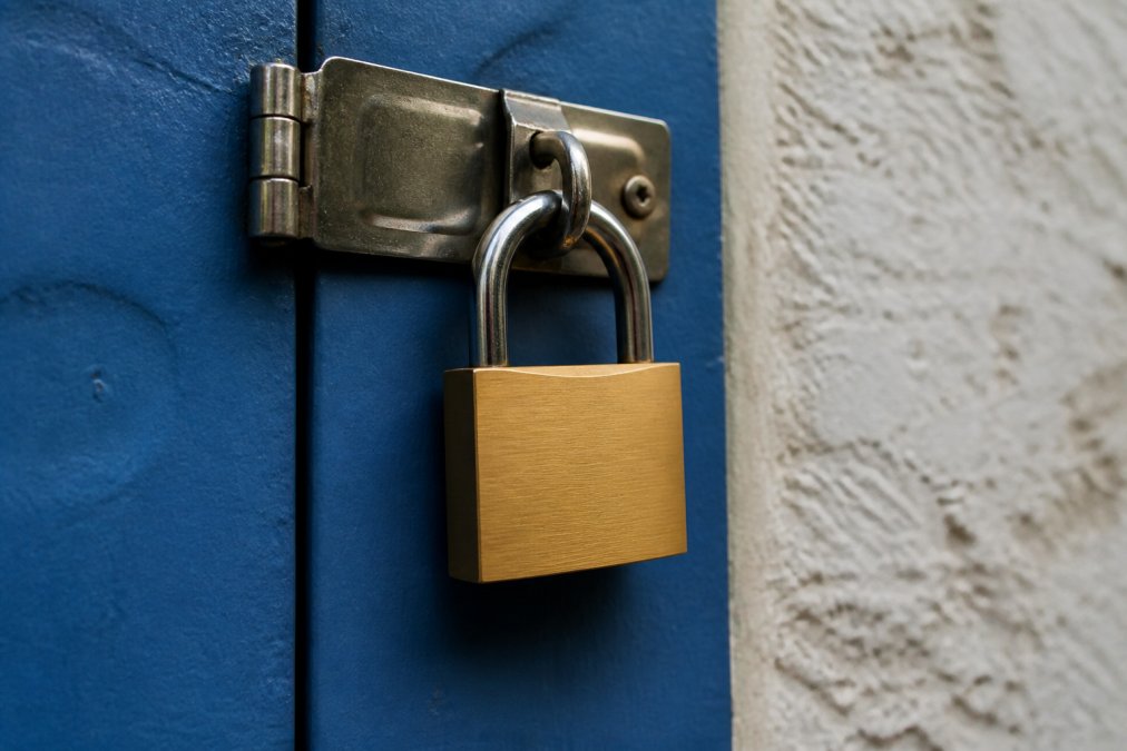 Close-up of smartphone screen displaying privacy settings menu with lock icon, padlock symbol, and security toggles visible, held in hand with blurred home background