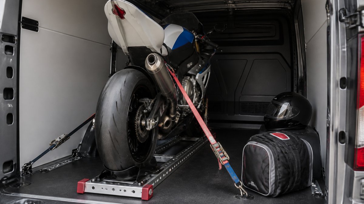 Track-prepared motorcycle secured for motorcycle transport for track days inside a clean van with kit.