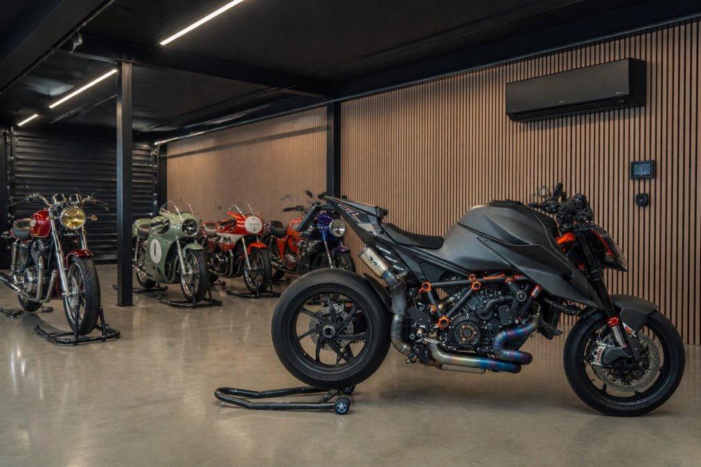 Interieur van een professioneel beveiligde motorfietsgarage met temperatuurcontrole, meerdere klassieke motoren op standaards, en duidelijk zichtbare klimaatregeling