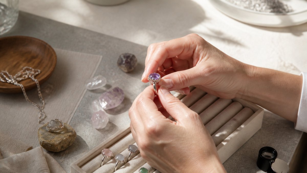 Close-up of hands carefully examining and inspecting sterling silver jewelry pieces and gemstones on a light surface with natural daylight