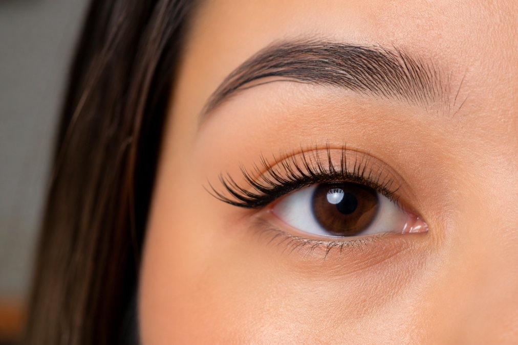 Close-up of person's eye with natural looking lash clusters applied in graduated pattern, showing proper placement from inner corner to outer corner with wispy spacing