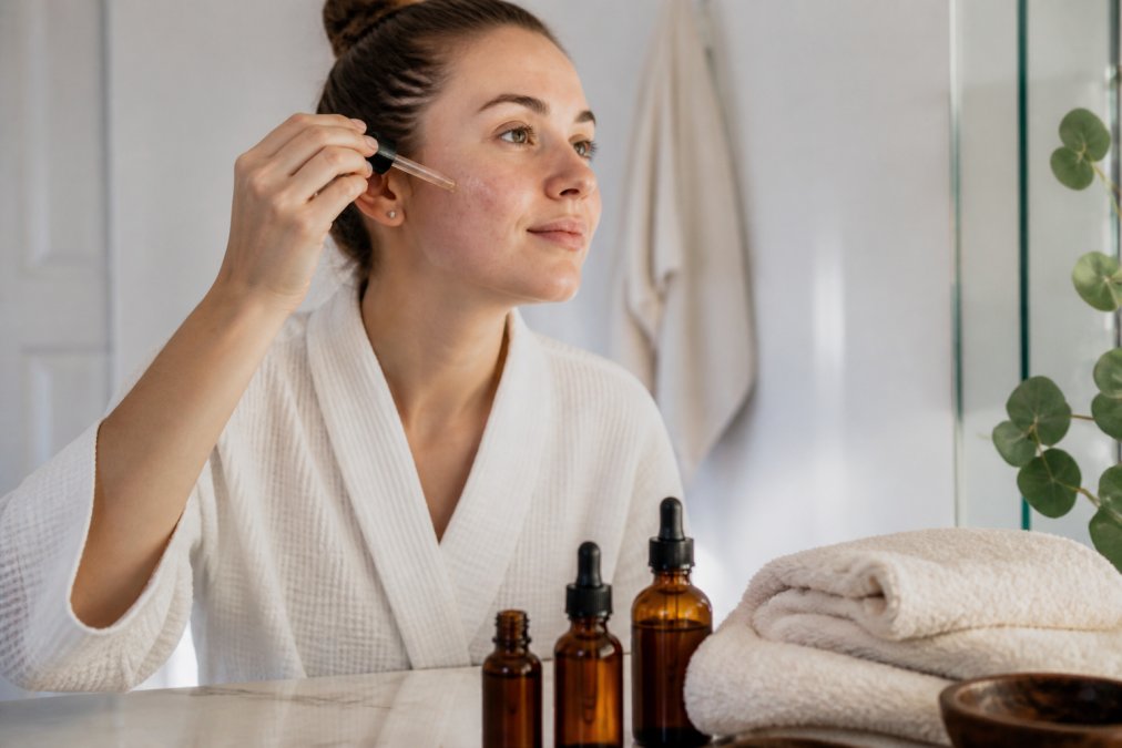 Woman with sensitive skin applying facial oil as one of the best natural retinol alternatives in a bright bathroom.
