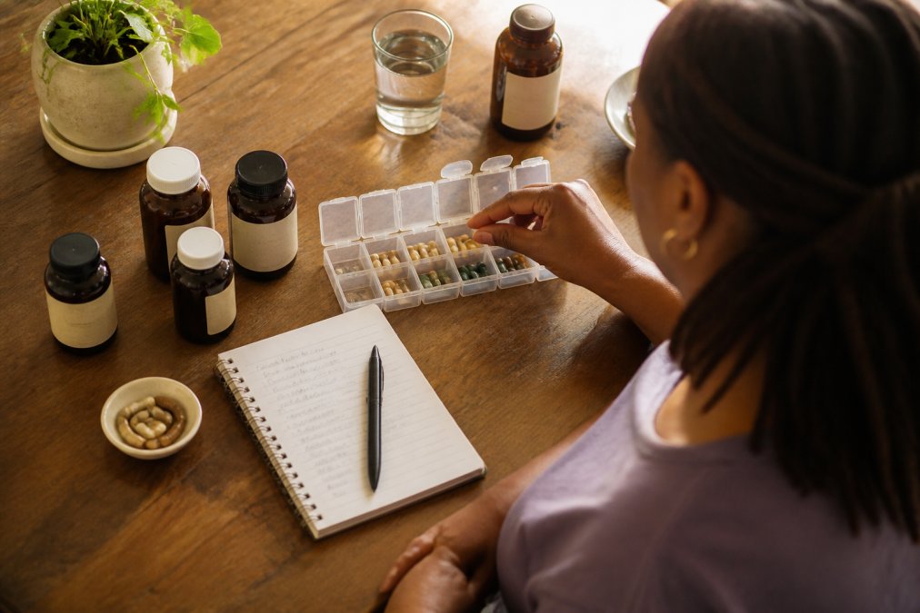 Weekly pill organizer and herbal supplements on a counter for a daily herbal protocol.