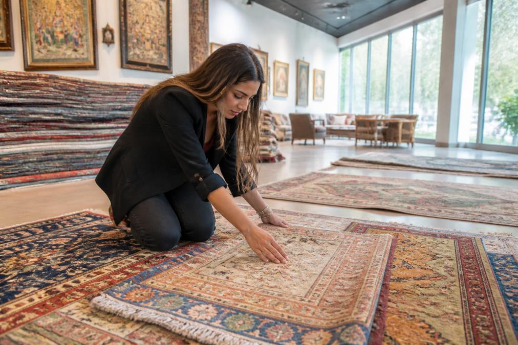Interior designer reviewing multiple curated rug samples laid out in a modern showroom with natural light streaming through large windows