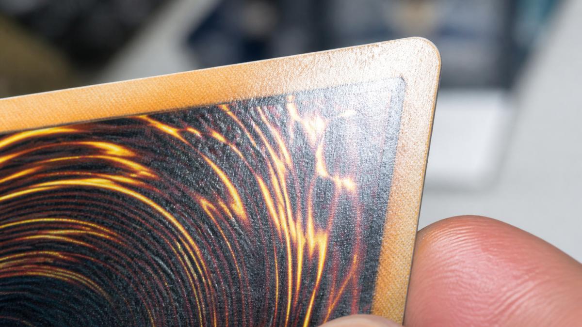 Close-up macro photography of trading card showing sharp corner detail, centering alignment marks, and surface gloss under bright magnification lighting