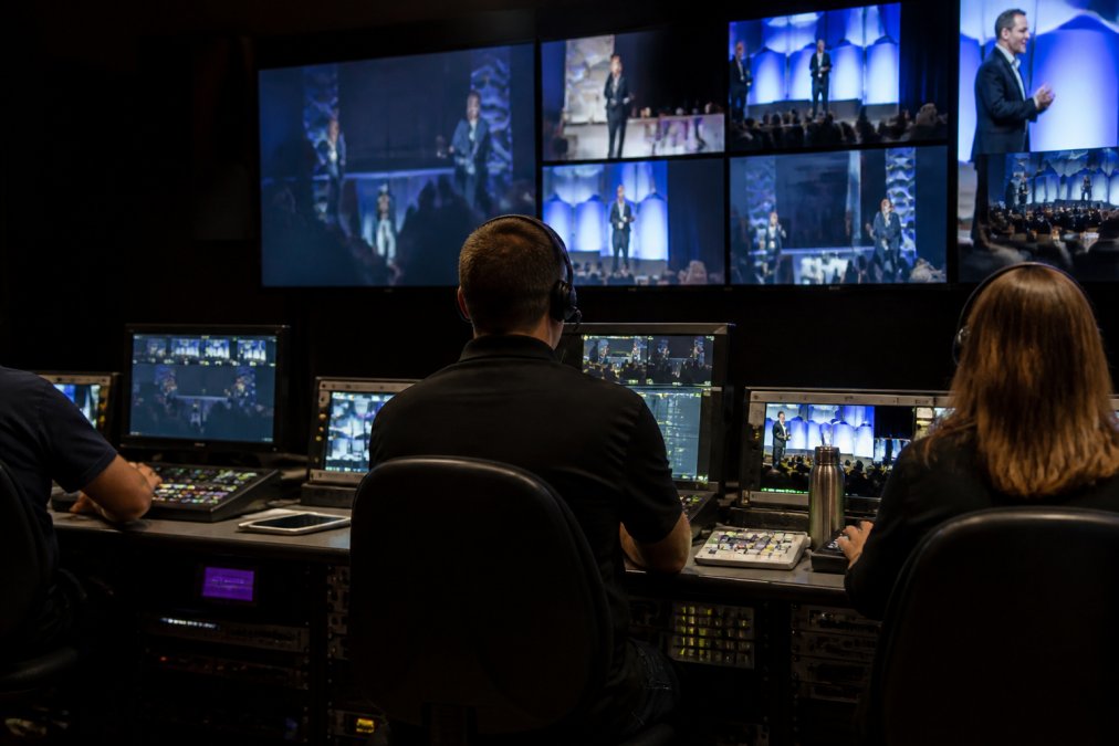 Professional broadcast control room with multiple monitors displaying real-time streaming metrics, engagement dashboards, and video feeds from multiple camera angles