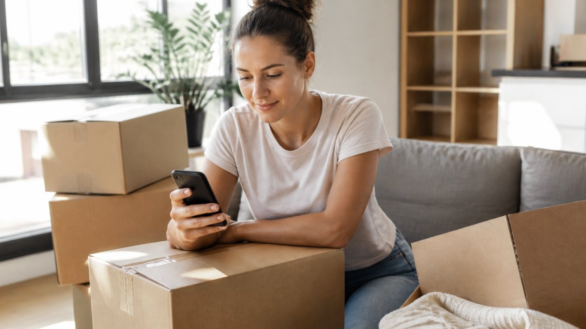 Person reviewing a moving quote with no hidden fees on a smartphone while sitting among packed boxes