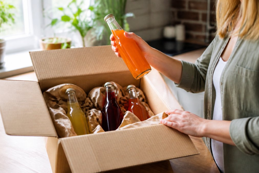 Person unpacking non-alcoholic drinks from a delivery box to check for damage, relevant to our non alcoholic drink return