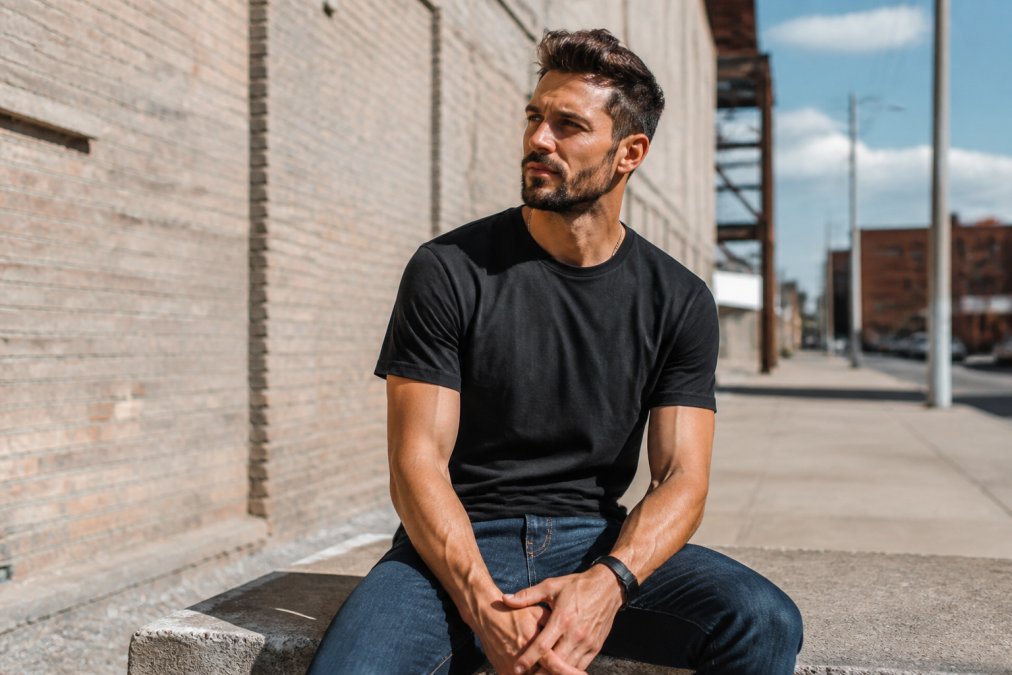 A man wearing a bold Christian graphic t-shirt in a casual outdoor urban setting, looking confident and approachable