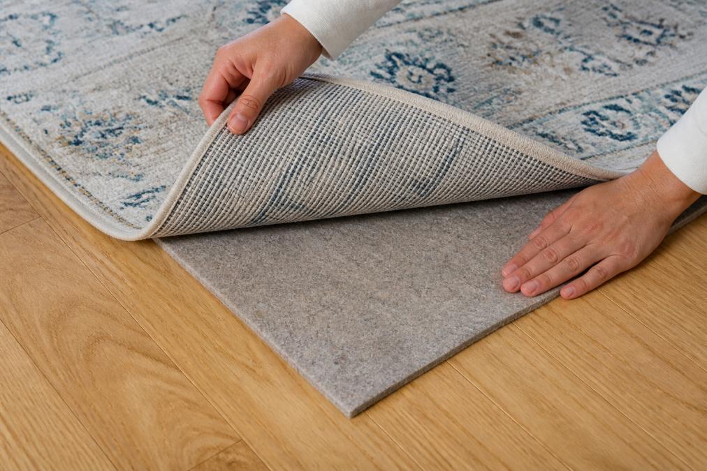 Diagram illustrating the step-by-step process for positioning a felt rug pad correctly on hardwood flooring.