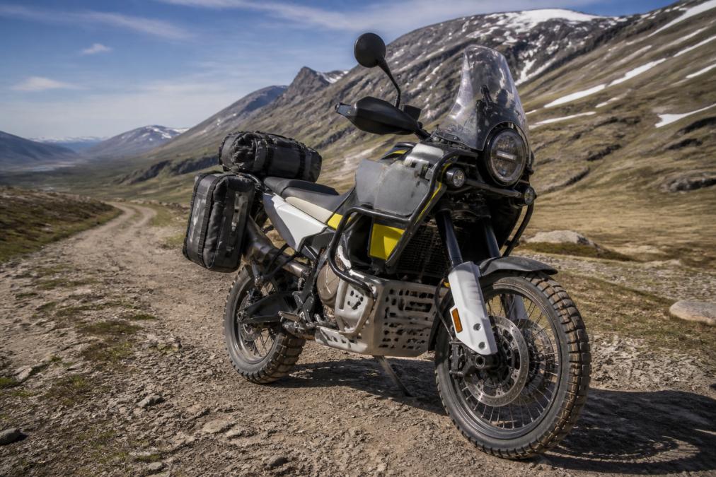 Volledig uitgeruste adventure motorfiets met bagage en bescherming geparkeerd op een onverhard bergpad.