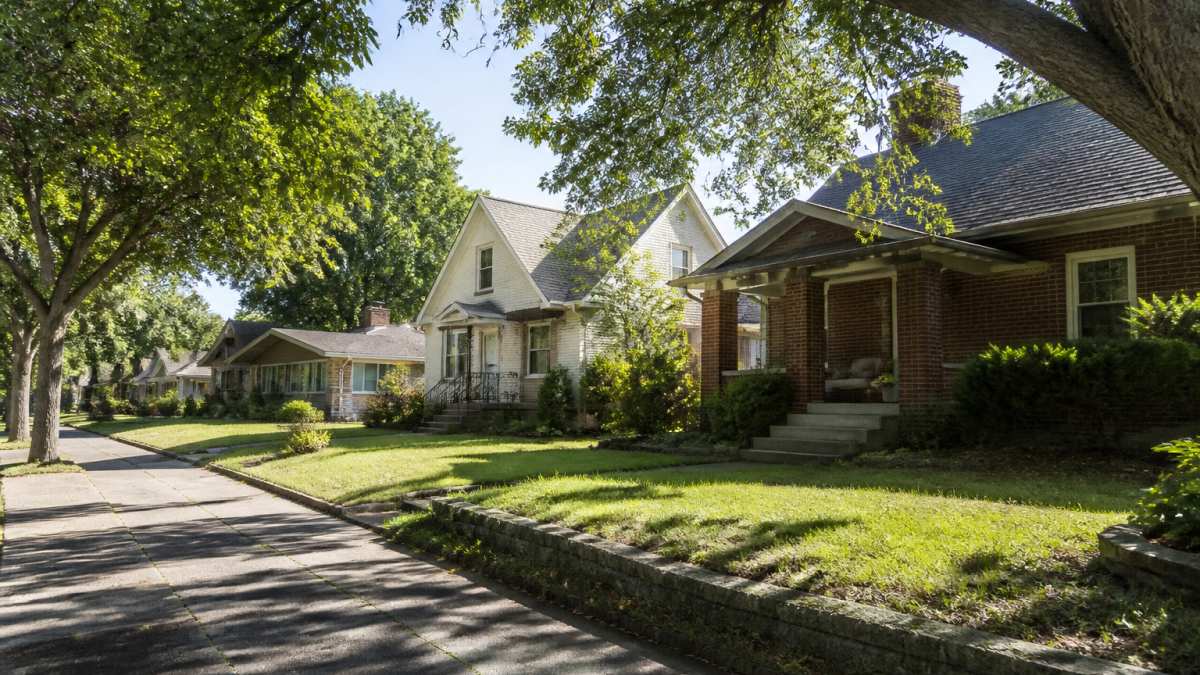 Tree-lined residential street showing a mix of historic and mid-century homes with varied lot sizes and architectural styles in a Boise neighborhood