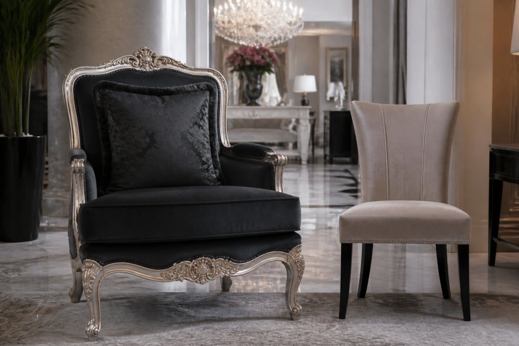 Elegante Hotelsuite mit einem schweren, verzierten Casa Padrino Sessel in Objektqualität neben einem zierlichen Haushaltsmöbel, das den Kontrast zwischen gewerblicher Robustheit und privater Leichtbauweise zeigt, in luxuriösem Interior mit Marmorboden und Kristallleuchter