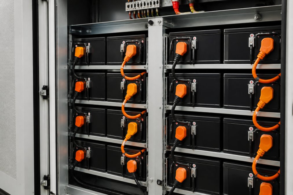 Interior view of a battery storage unit with lithium-ion battery banks and electrical connections in a clean, professional installation setup
