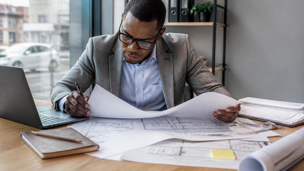 Investor reviewing blueprints and contracts to evaluate off-plan property investment risks at a desk.
