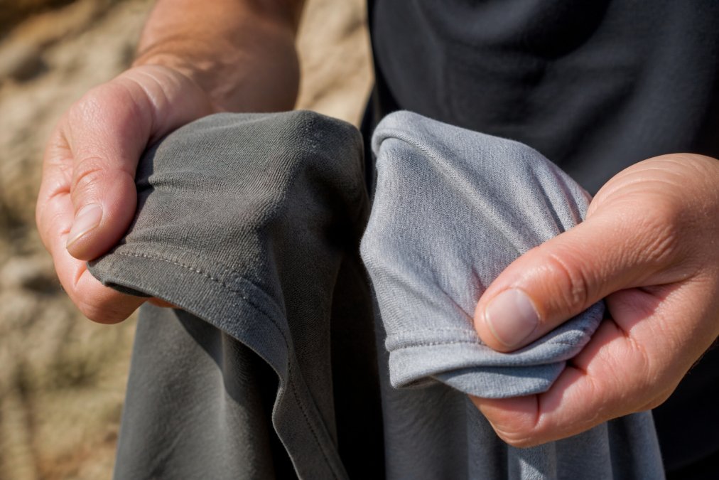 Close-up of a rider's hands gripping the thick fabric of a heavyweight cotton t-shirt next to a thinner standard tee, showing the visible difference in material density in warm natural light