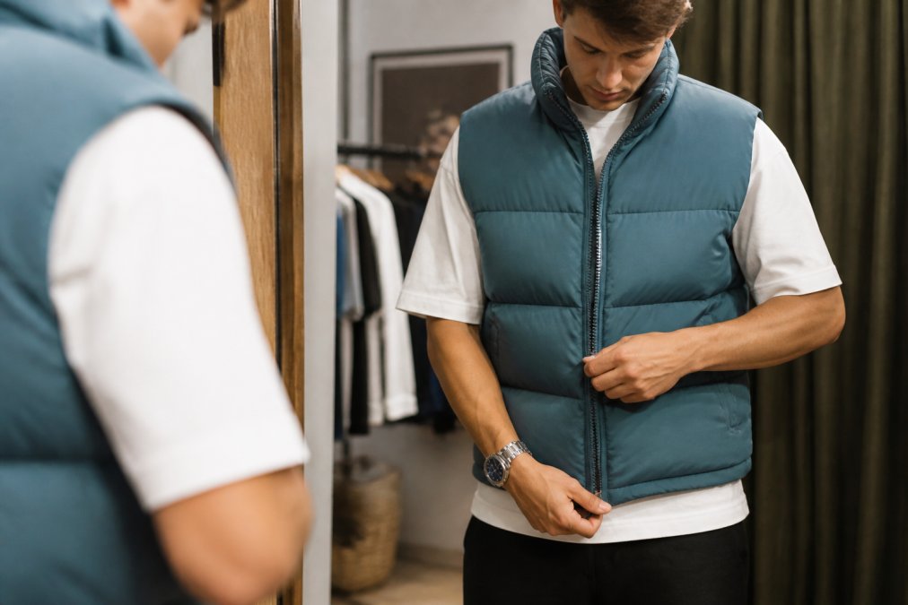 Close-up van iemand die een streetwear T-shirt aanpast, waarbij je de pasvorm, de lengte en de details van het kledingstuk ziet in natuurlijk licht