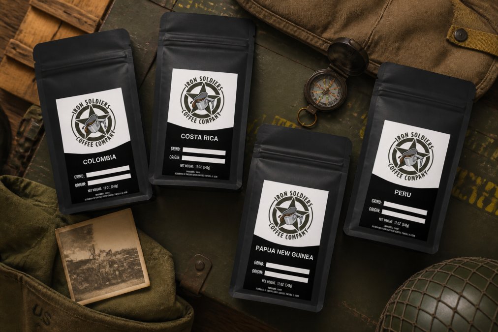 Overhead shot of multiple Iron Soldiers Coffee bags displaying different single-origin labels (Colombia, Costa Rica, Peru, Papua New Guinea) arranged on a tactical surface with vintage military memorabilia and a vintage compass