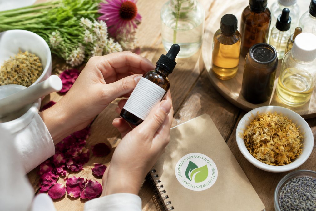 Hands holding a skincare bottle and examining the ingredient label closely in natural daylight, surrounded by botanical ingredients like flower petals, dried herbs, and essential oil bottles on a natural wood surface