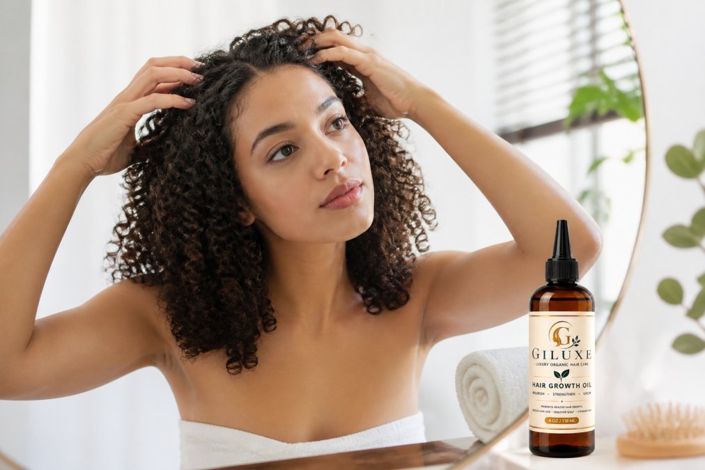 Person applying organic hair oil to their scalp with fingertips, demonstrating scalp massage technique in a bright, clean bathroom setting with natural lighting