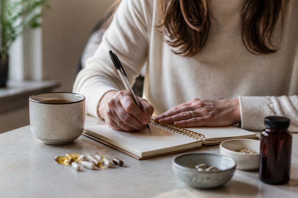 Vrouw met notitieboek en thee bereidt zich voor op orthomoleculaire therapie kosten bespreking tijdens haar afspraak.