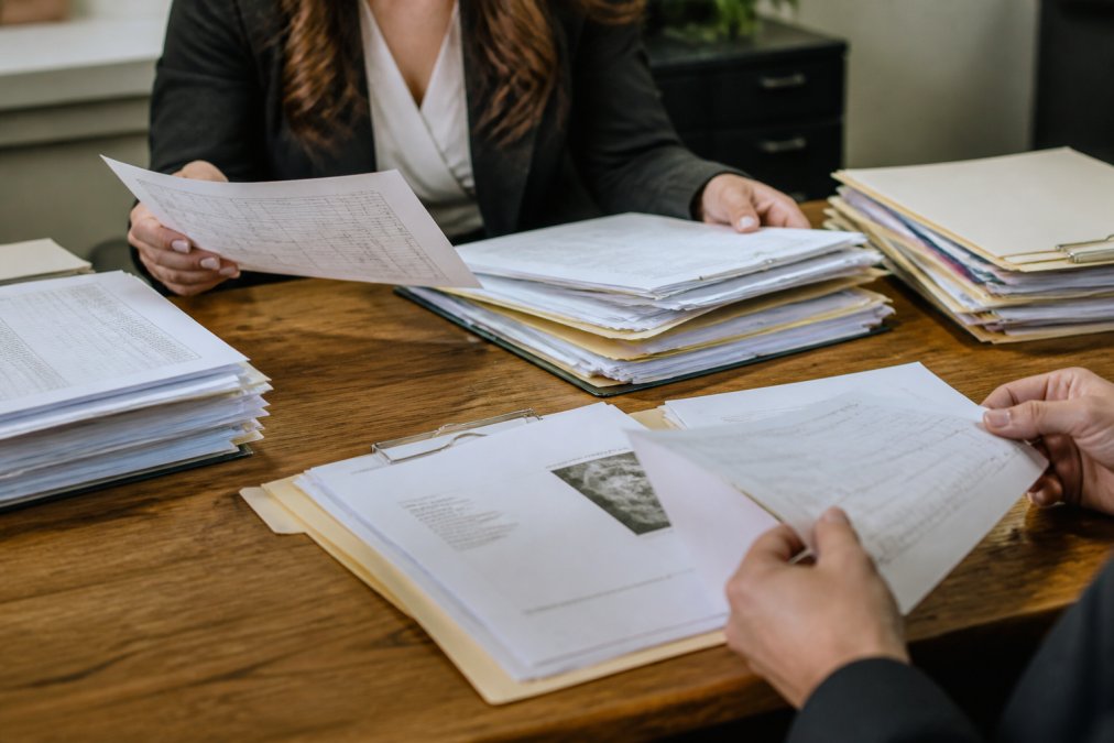 Organized medical records, therapy notes, and documentation folders spread across a table with hands holding key documents
