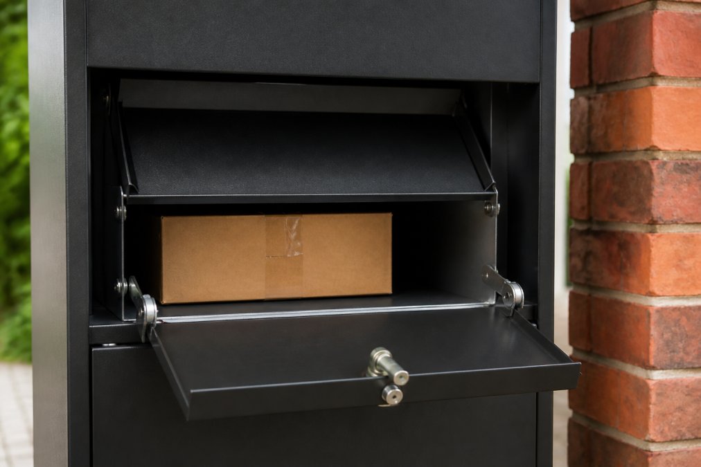 Close-up van anti-hengelsysteem in pakketbrievenbus met zichtbare inklapbare flap, beveiliging tegen terugtrrekken en uitnameklep met cilinderslot, moderne constructie in staal