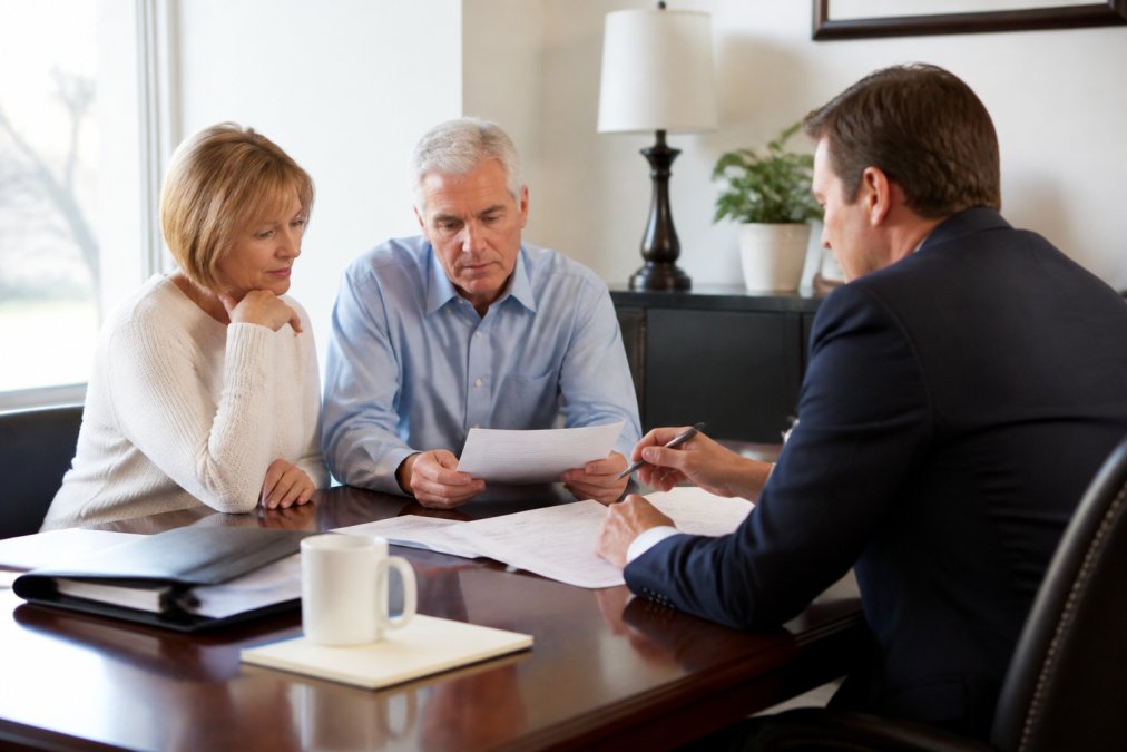 A couple consulting with pension financial advisors in a bright office while reviewing documents