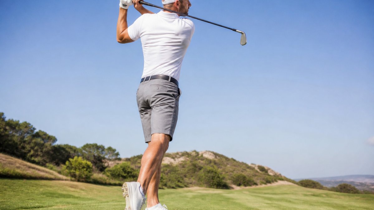 A golfer mid-swing on a sunny fairway, showing how stretch golf shorts move with the hips and shoulders without pulling or riding up