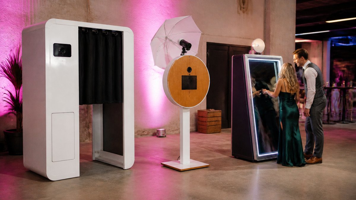 Gasten maken foto's in een moderne spiegelbooth op een bedrijfsfeest, met heldere LED-verlichting en digitaal touchscreen zichtbaar, terwijl twee personen lachen naar het scherm