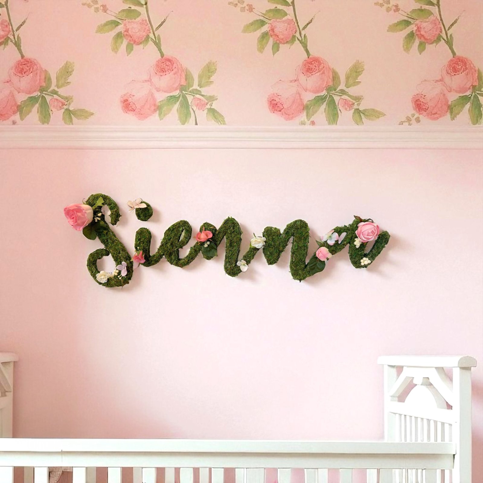 Moss wooden letters with roses hang in cursive font, hangs in baby room. Rose theme.