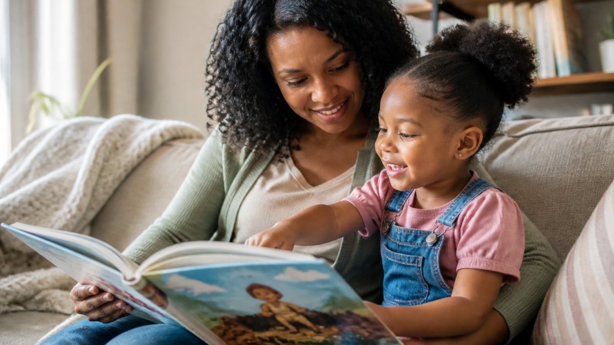 A parent and child sitting on a cozy couch reading a colorful picture book together and smiling.