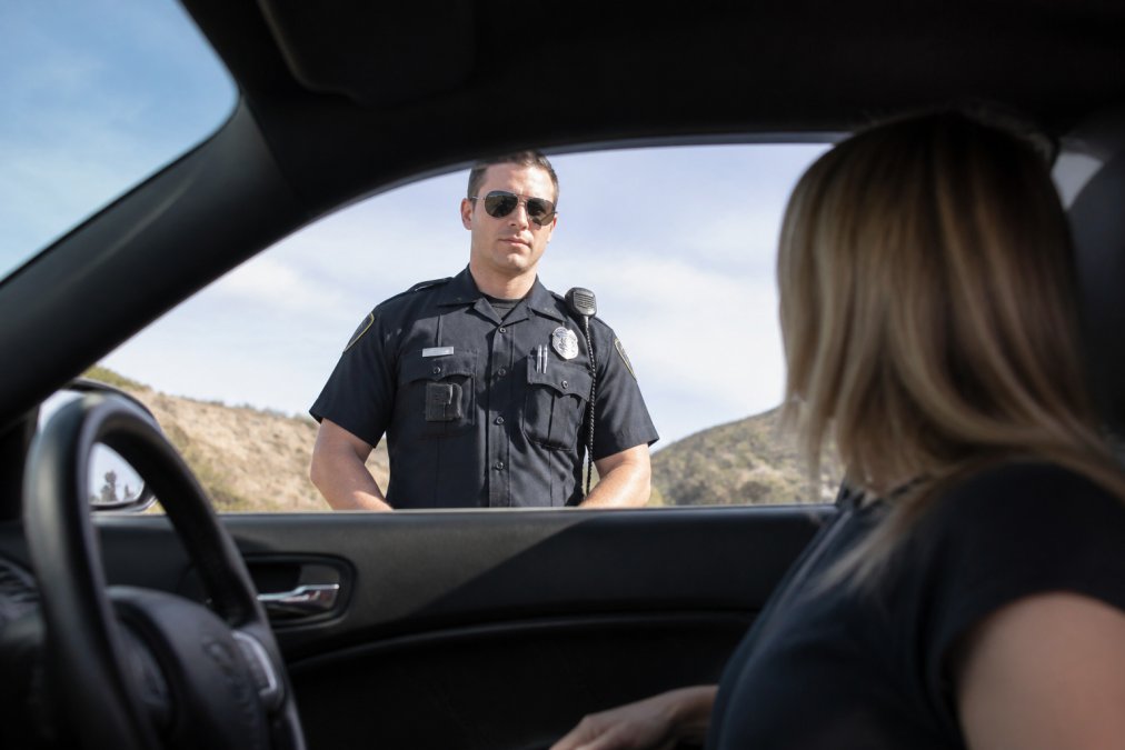 Police officer conducting a traffic stop, visible from the driver's window perspective, showing the officer's stance and visibility during a routine vehicle interaction