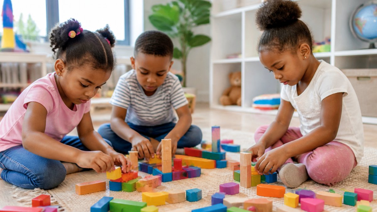 Young children engaged in hands-on exploration with building blocks and learning materials on a bright, open play surface