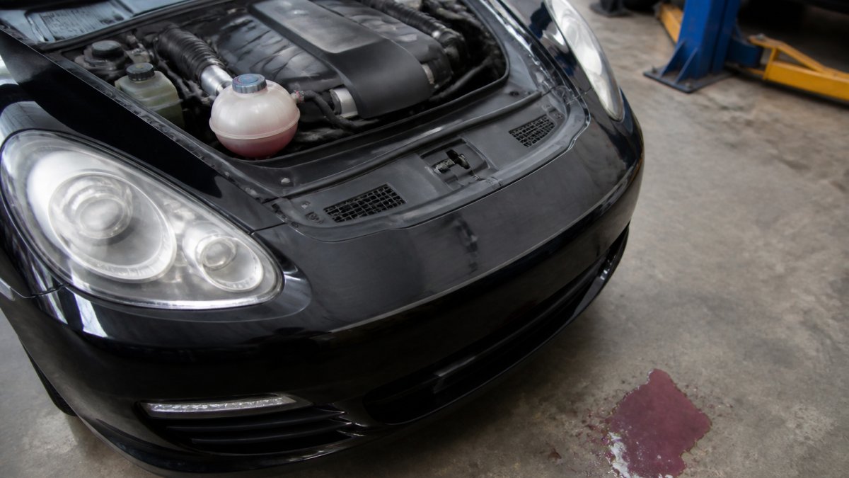 Infographic showing the engine cooling system and signs of fluid loss on a garage floor beneath the vehicle front.