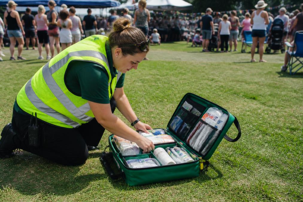 Event organizer checking portable medical supplies in a first aid kit at an outdoor community gathering