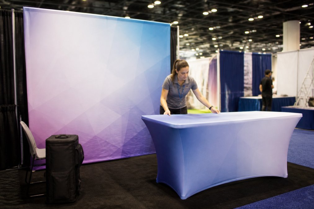 Step-by-step diagram showing the assembly of a fabric wall and table display for a small convention booth space.
