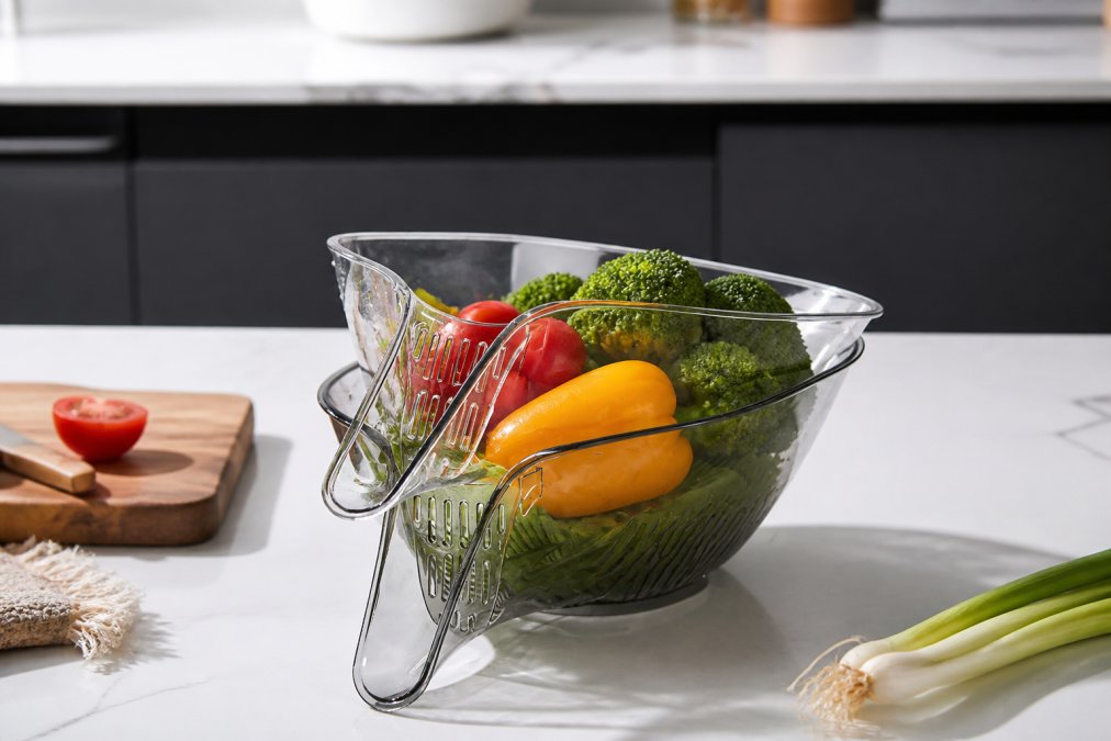 Kitchen counter scene with a Heat Guard drainage basket filled with fresh vegetables during meal prep, showing the bowl-shaped design and practical utility