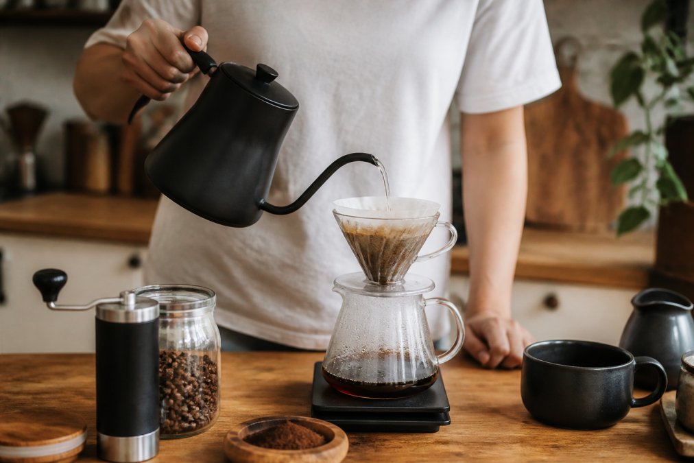 Pouring hot water from a gooseneck kettle over grounds to brew premium coffee using a pour-over dripper.