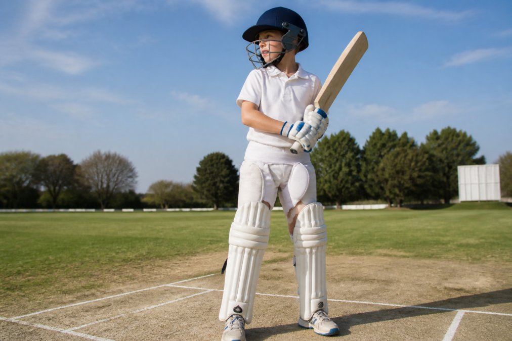 Young cricketer wearing premium cricket gear at the crease during a sunny match
