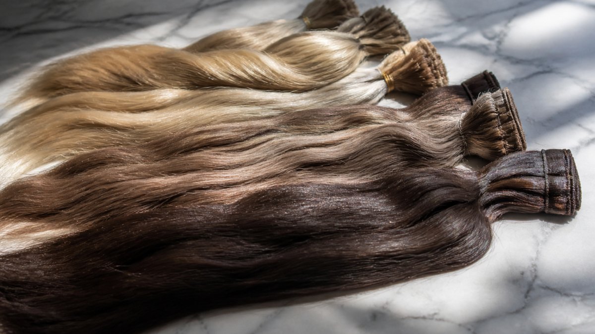 Close-up of raw human hair bundles laid out on a marble surface, showing natural variation in tone and texture under soft window light