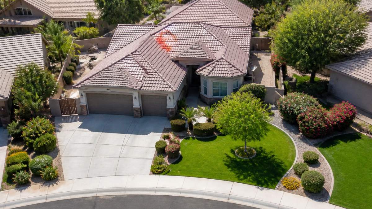 Well-maintained residential property with manicured landscaping, clean driveway, and clear yard viewed from an elevated angle showing outdoor spaces and property layout