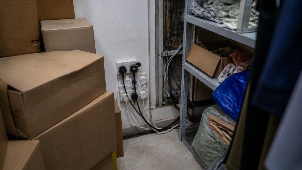 Retail stockroom showing cardboard boxes stacked near electrical outlets, exposed wiring behind shelving units, and cluttered storage areas with combustible materials