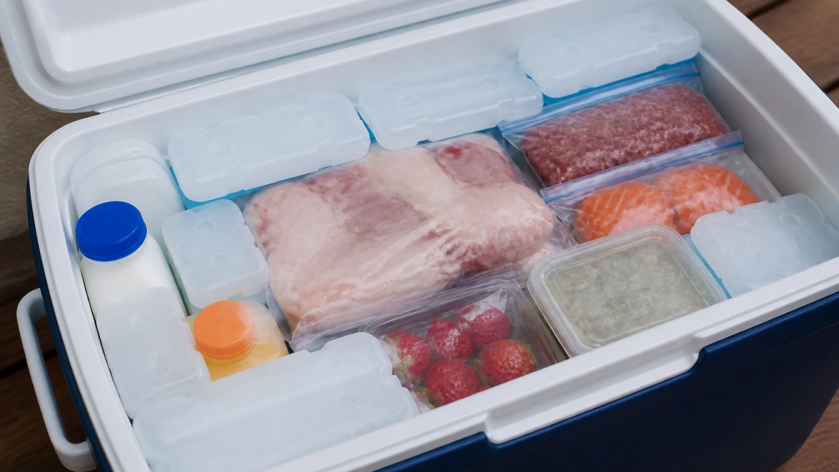 Close-up of a cooler packed with ice packs and perishable food items arranged in layers, showing proper organisation and storage during a power outage