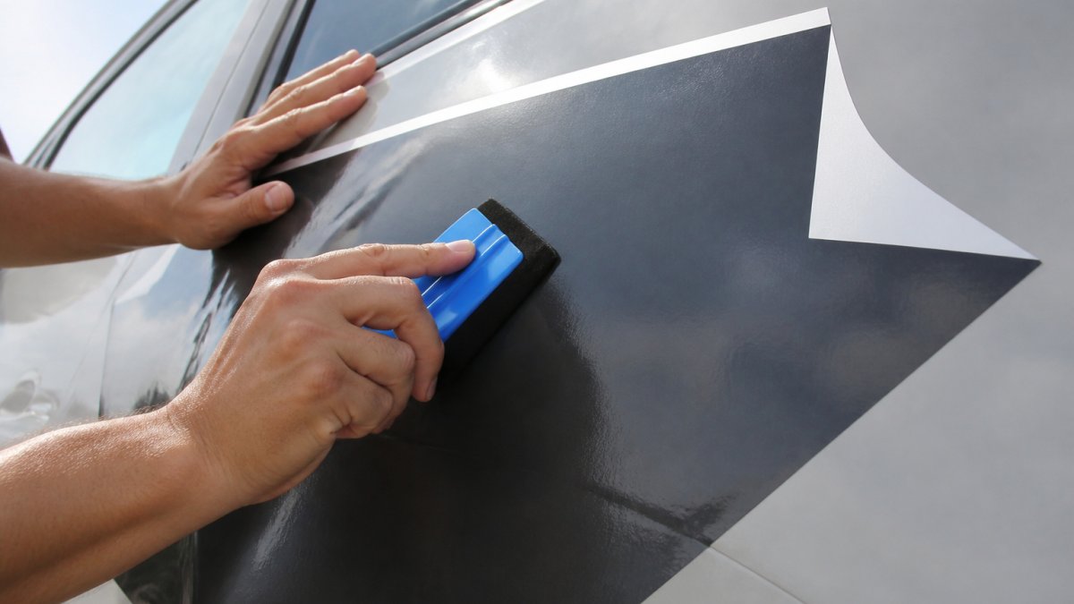 Diagram illustrating the process of smoothing a vinyl decal onto a surface using a squeegee at a 45-degree angle.