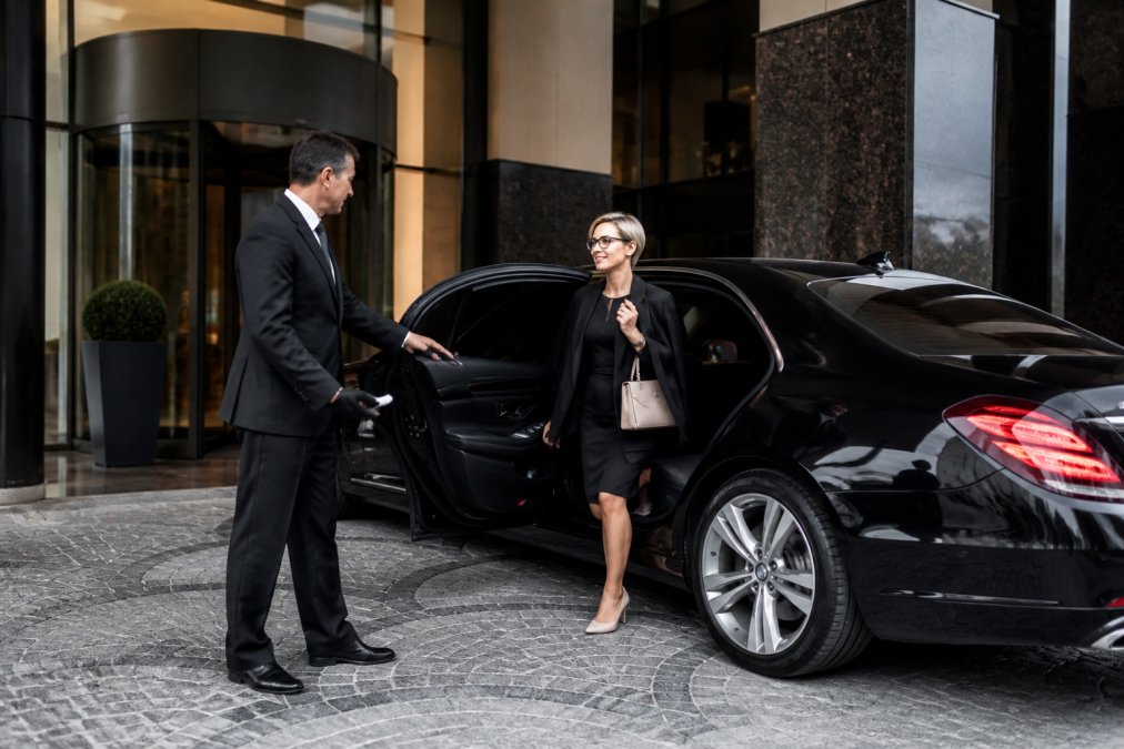 Professional chauffeur opening the door of a luxury sedan for a passenger during a private car service in St Petersburg