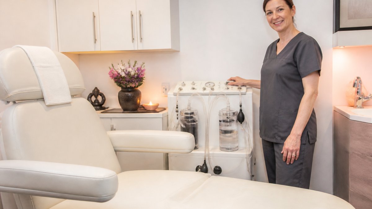 Professional therapist in calm, private treatment room with soft warm lighting, comfortable medical chair, and clean clinical environment conveying professionalism and privacy