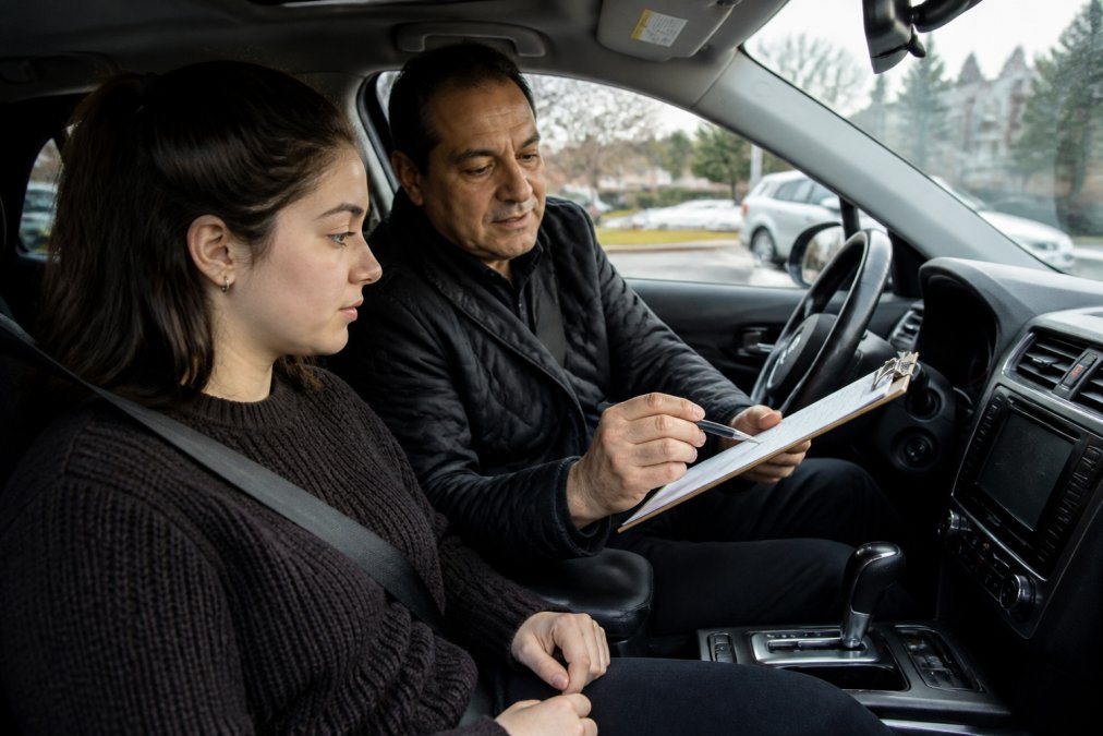 Certified instructor guiding a student during private driving lessons with pickup on a busy city street