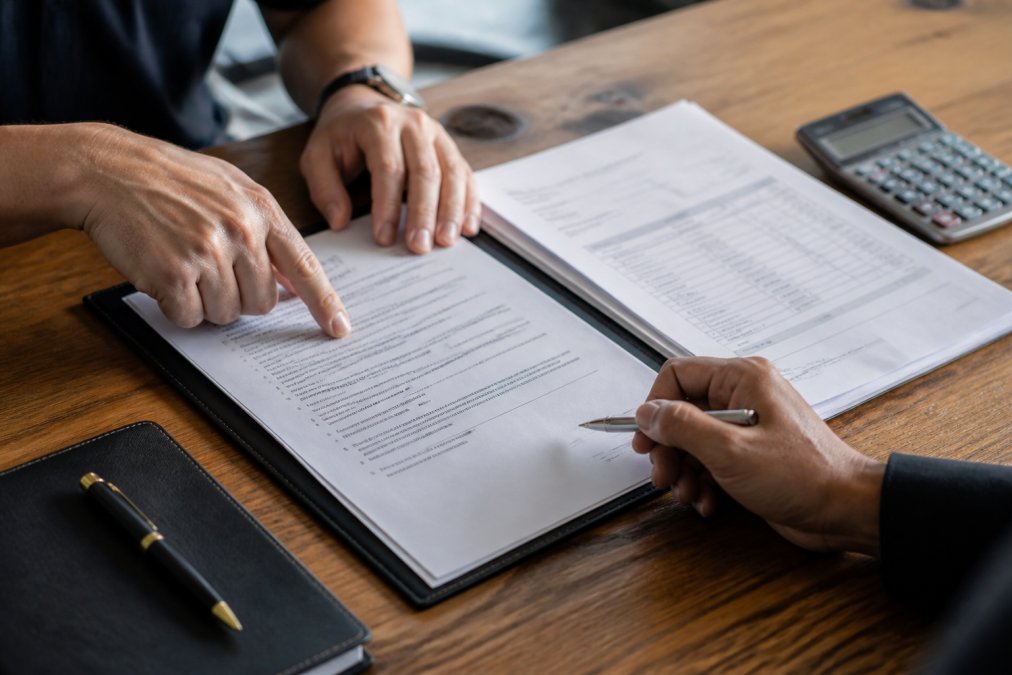 Close-up of a charter contract and invoice being reviewed at a wooden desk with a pen and calculator nearby